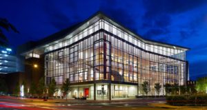 The Durham Performing Arts Center is an all-glass and steel framed building lit up at night.