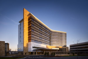 The North Carolina Heart & Vascular Hospital is a tall building of modern architcture, framd by the sunset.